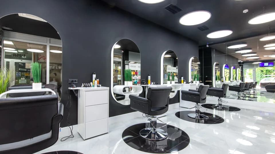 Salon de coiffure moderne, fauteuils alignés devant des miroirs en arche