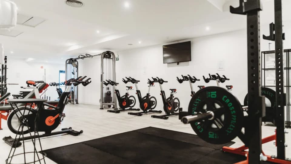 Salle de sport avec vélos, racks de musculation et disques